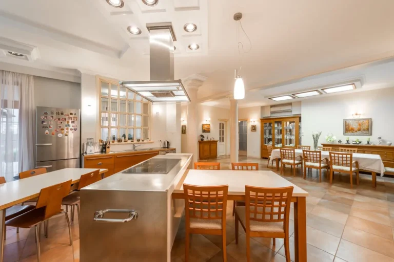 Cozinha e sala de jantar integradas com iluminação embutida no teto, luminárias pendentes e luz natural, criando ambiente sofisticado e funcional com iluminação planejada.”