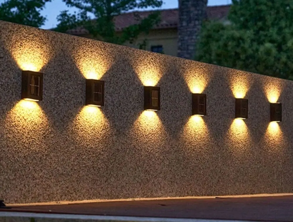 Luminárias de parede com sensor de presença iluminando muro externo com fachos simétricos, destaque para iluminação inteligente e econômica