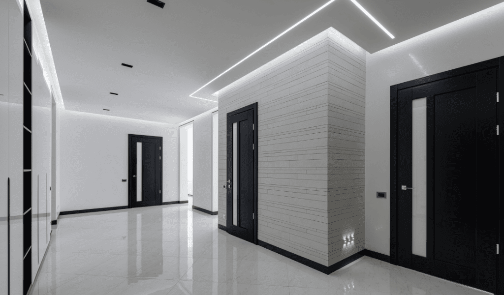 “Corredor moderno com iluminação indireta em LED embutido no teto e rodapé, destacando design minimalista e atmosfera elegante e relaxante.