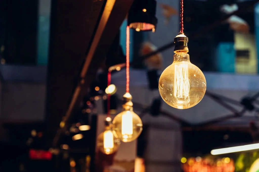 “Lâmpadas incandescentes pendentes com filamento exposto em ambiente moderno, destacando a temperatura de cor quente da iluminação.